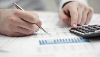Financial data analyzing. Counting on calculator.